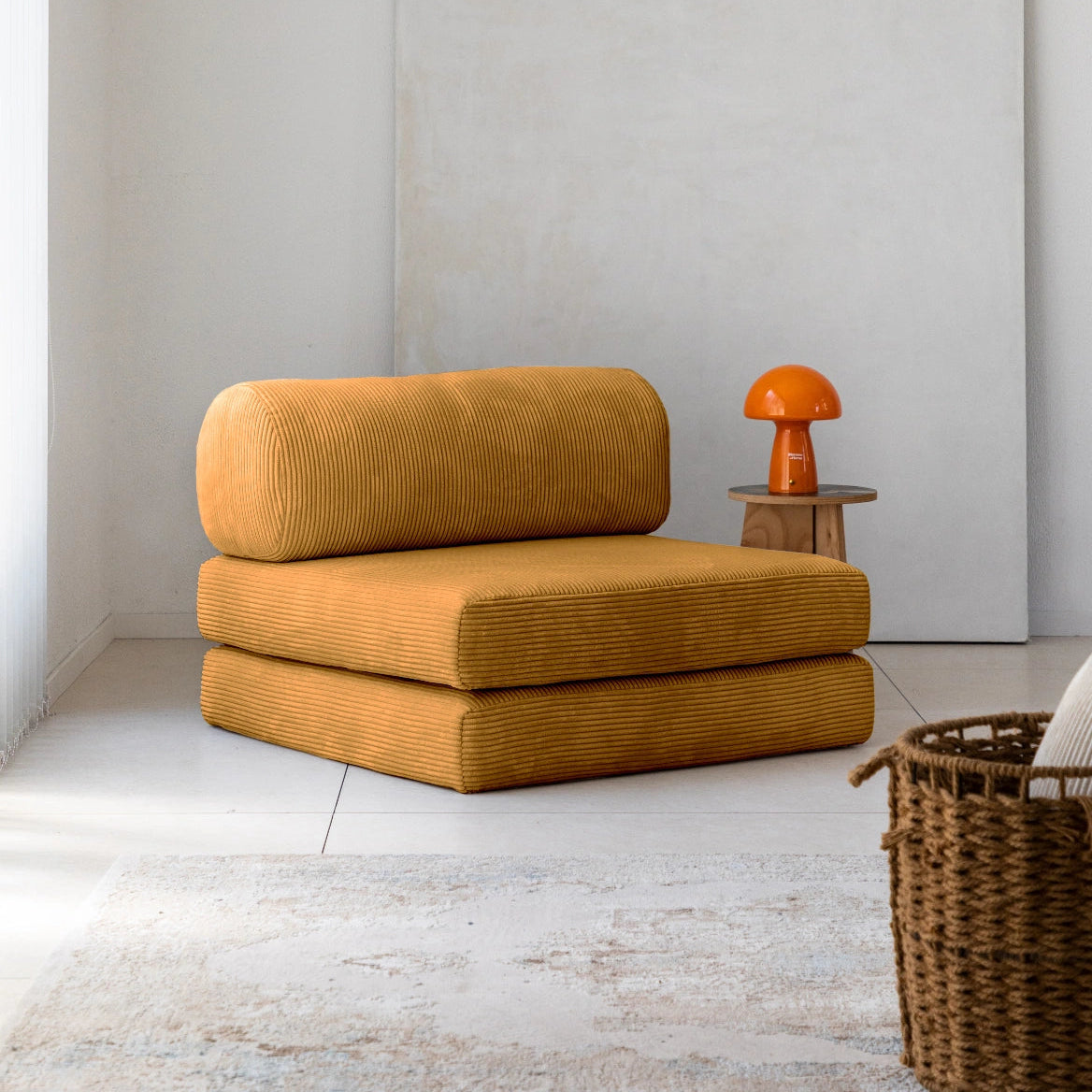 Mustard-colored modular sofa in a minimalistic room with a white wall and wooden floor.